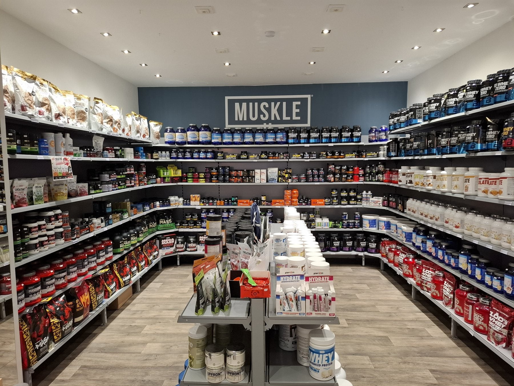 Interieur van MUSKLE Antwerpen met centrale gang, productstellingen en groot MUSKLE-logo op de achterwand