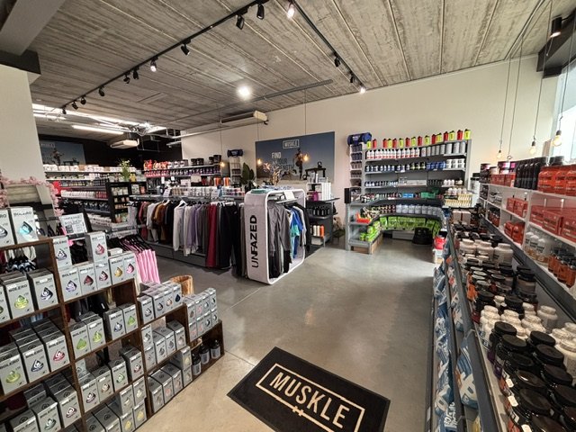 Interieur van MUSKLE Begijnendijk met MUSKLE-mat, kledingrekken en supplementenwand