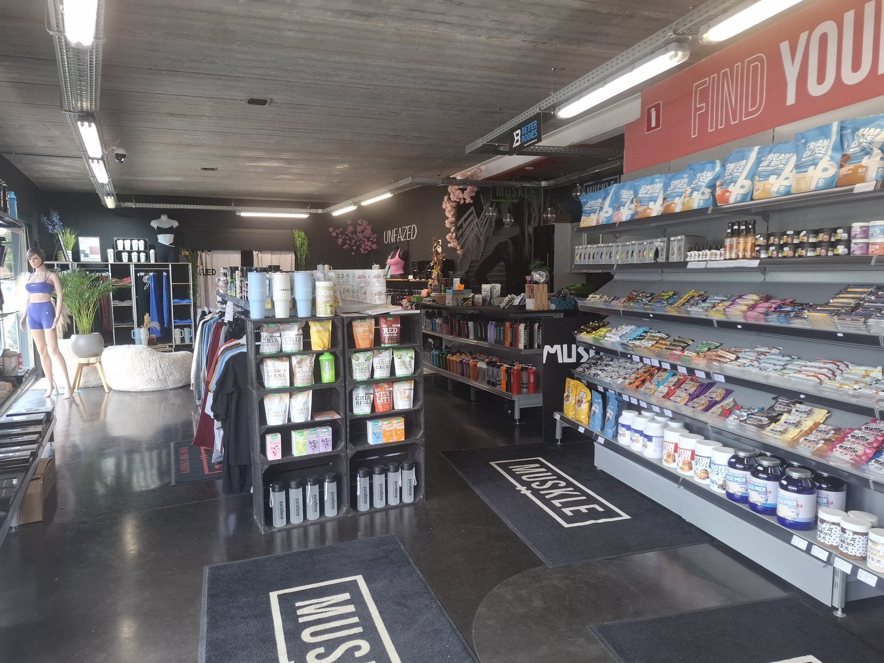 Interieur van MUSKLE Bonheiden met supplementenwand, kledingrekken en MUSKLE-matten