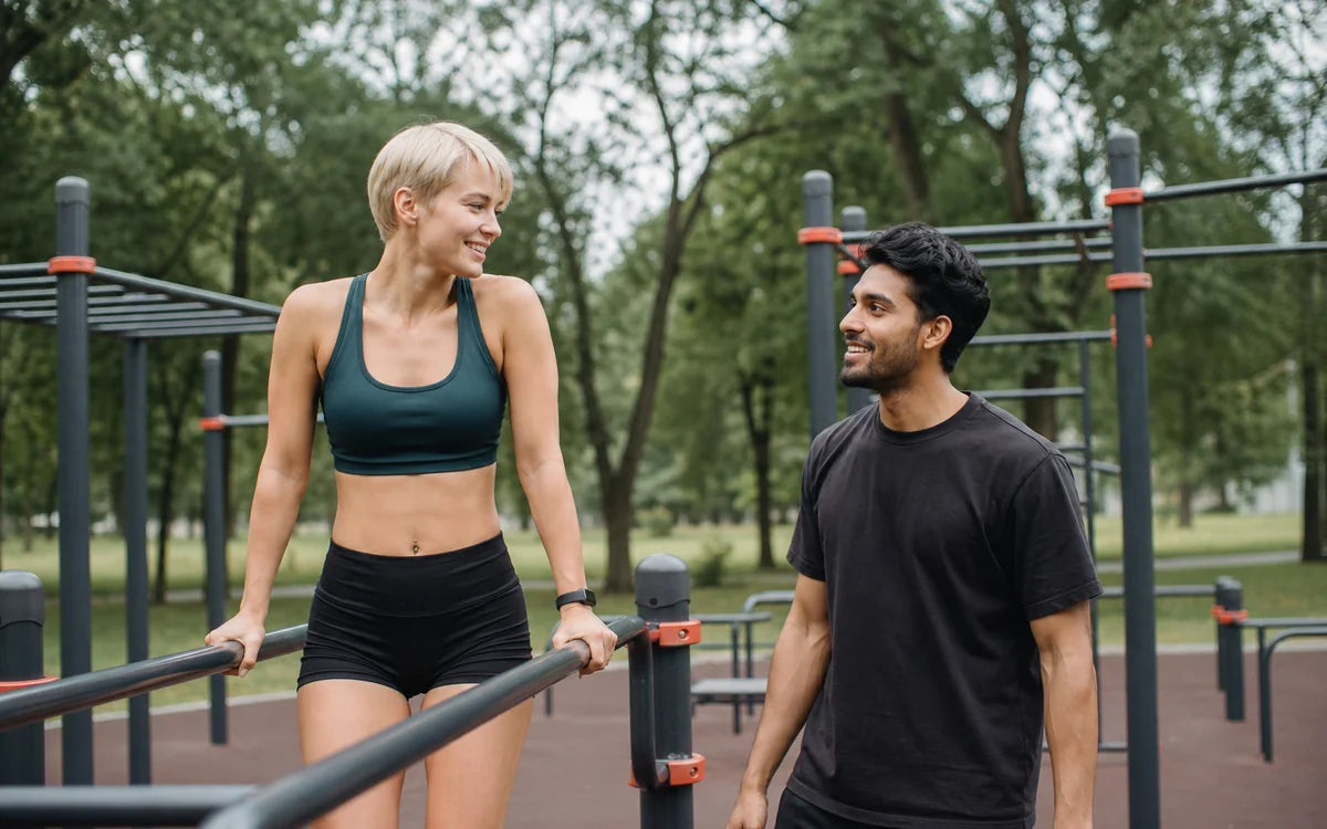 Jongvolwassen vrouw en man tijdens outdoor calisthenics in een trainingspark
