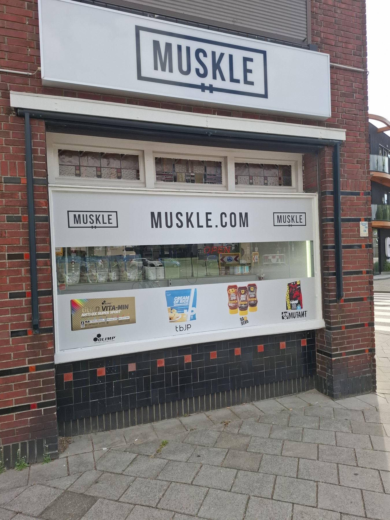 Display window of MUSKLE Roosendaal with MUSKLE signage and OPEN sign
